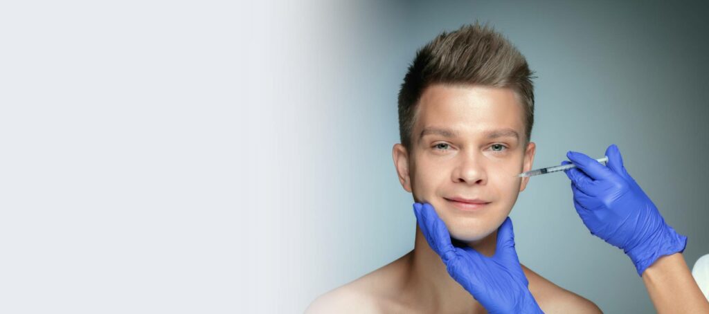 A man smiling while a medical professional in blue gloves administers a facial injection
