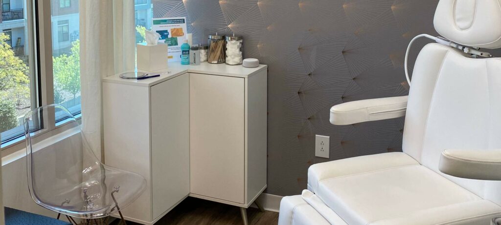 Minimalist treatment room with a white medical chair, countertop, and large window