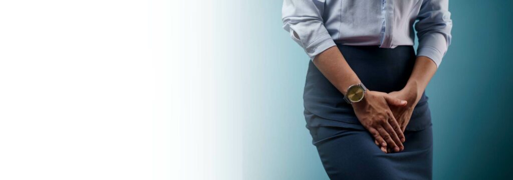 A woman in business attire holding her lower abdomen, indicating pelvic discomfort