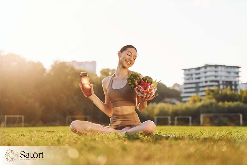 Woman in exercise outfit sitting on green grass holding healthy food, promoting wellness and healthy lifestyle