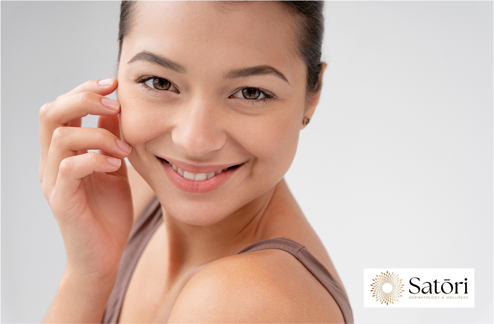 Close-up of a smiling woman looking at the camera, showcasing natural facial volume after dermal filler treatment.