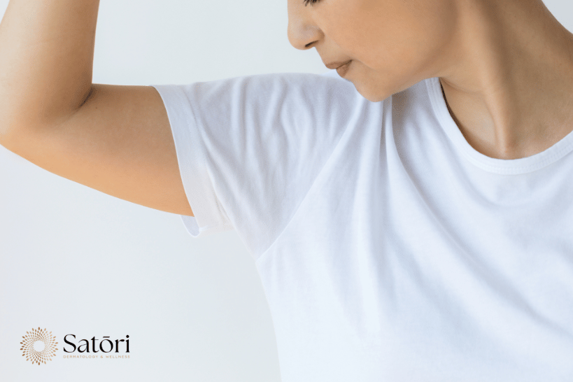 Woman in white shirt raising arms showing underarm sweating