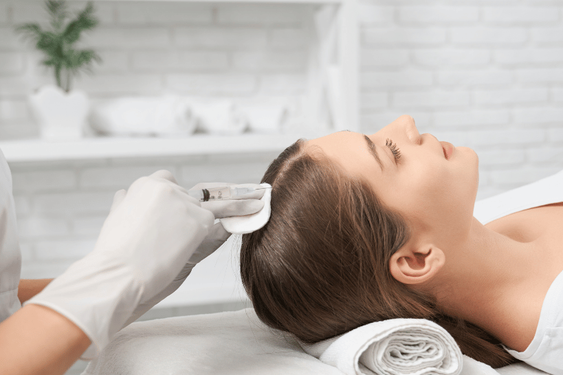 Woman lying in a treatment room receiving stem cell therapy injection for hair restoration